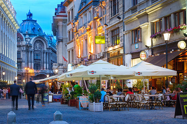 People sit at cafes and walk in the old town of Bucharest, Romania.