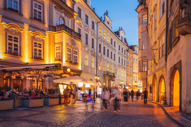 Tourists walking down an old town street in Prague in the evening.